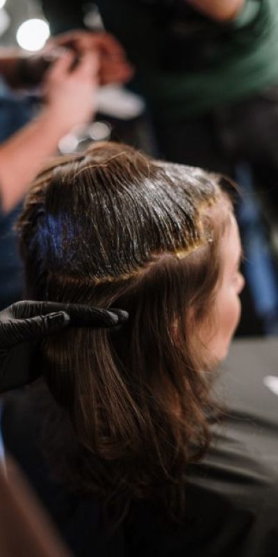 Woman receiving hair coloring treatment in a modern salon setting.