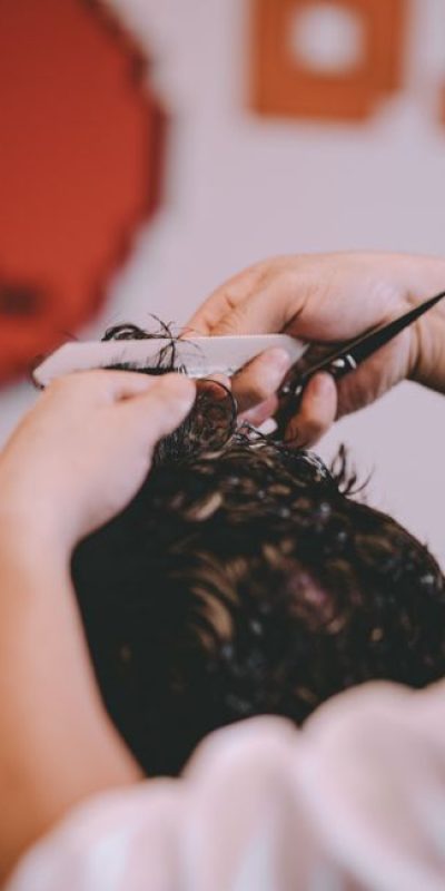 From above of crop anonymous master cutting hair of male client in modern barbershop